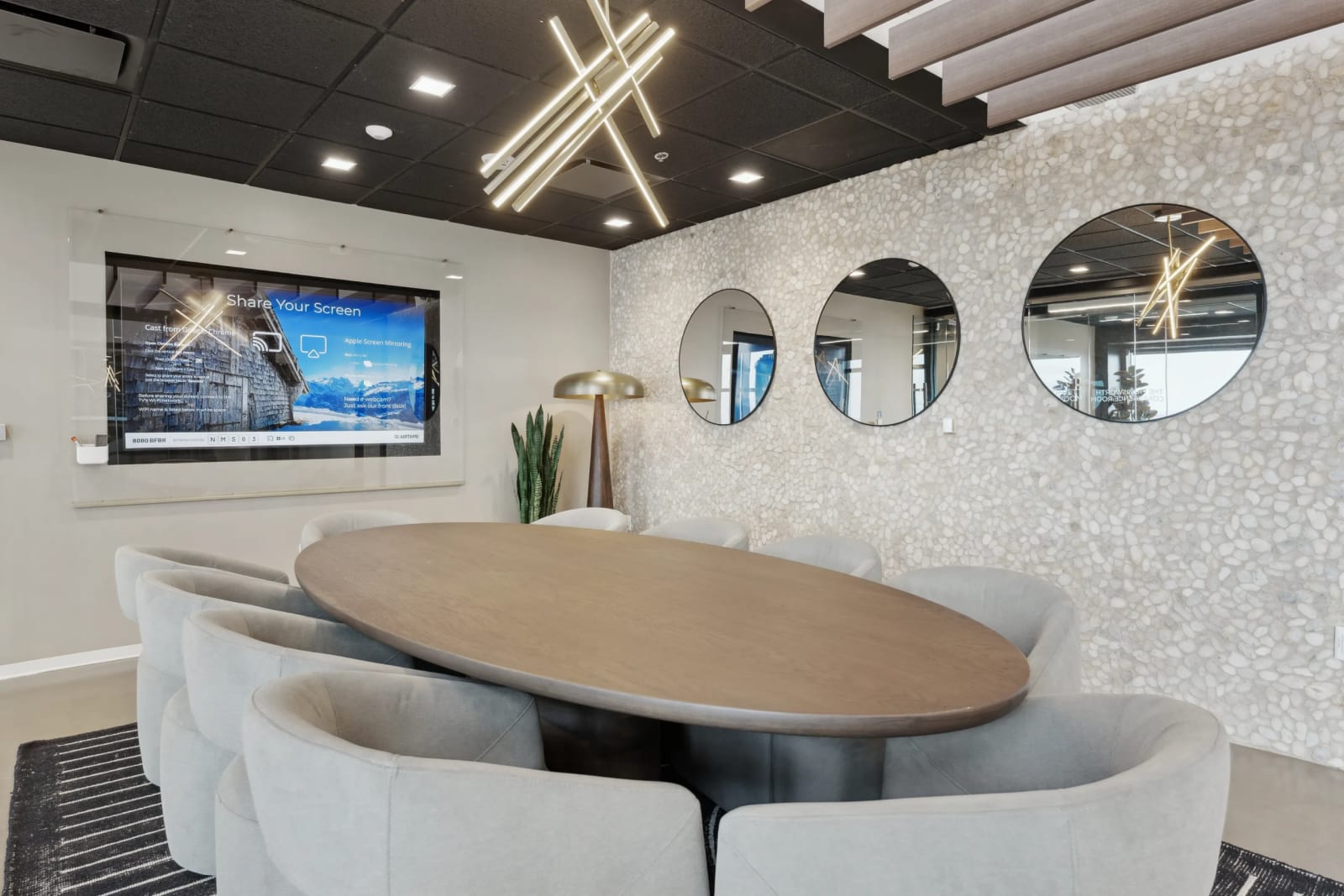 Boardroom with oval table, pendant lighting, and decorative mirrors at Lucid Private Offices