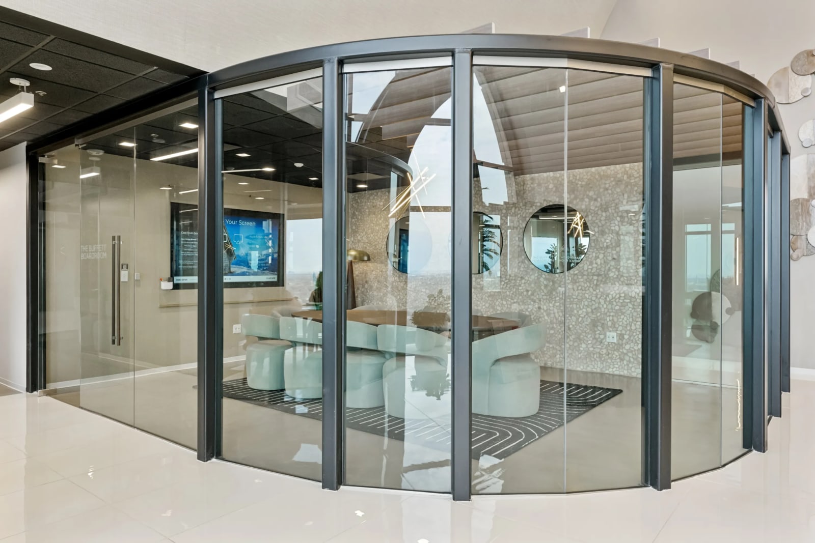 Glass-walled meeting room with conference table, TV screen, and plants at Lucid Private Offices