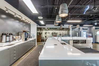 Contemporary kitchenette with stainless appliances, large island counters, and open views into office spaces