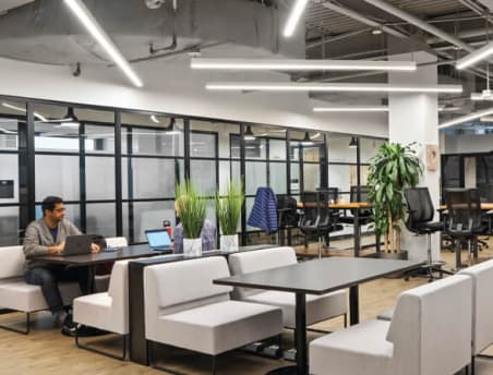 Business team meeting in a Lucid Private Offices conference room with stone wall and modern art
