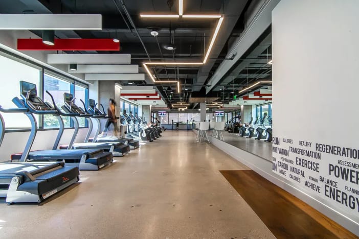 Modern fitness center near Lucid Private Offices Dallas Galleria with cardio equipment and motivational word wall