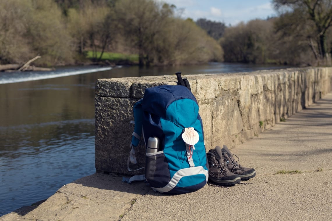 Mochila y zapatillas al costado de un río