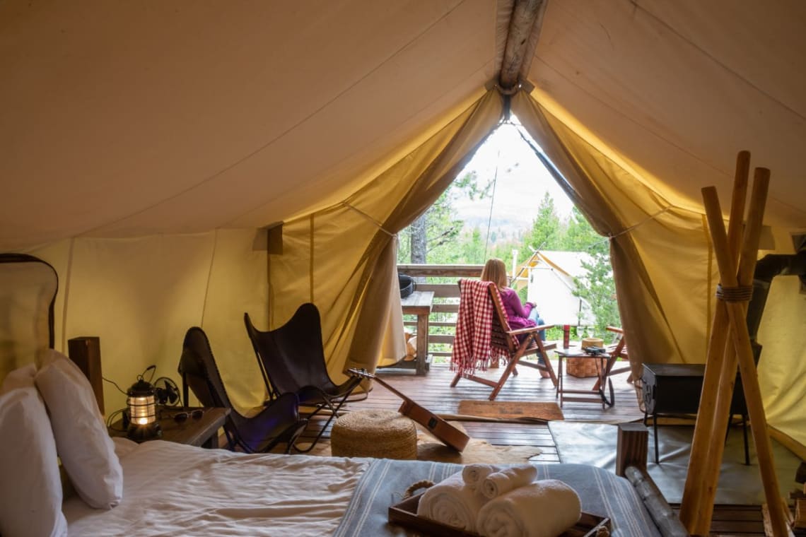 Mujer sentada en la terraza de su carpa de glamping