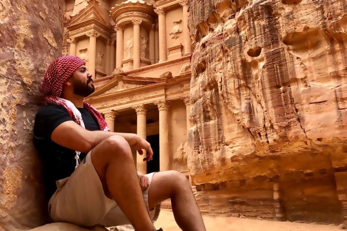 Joven sentado reflexionando en Petra, Jordania