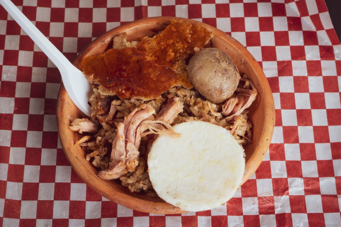 Cazuela con lechona y una arepa