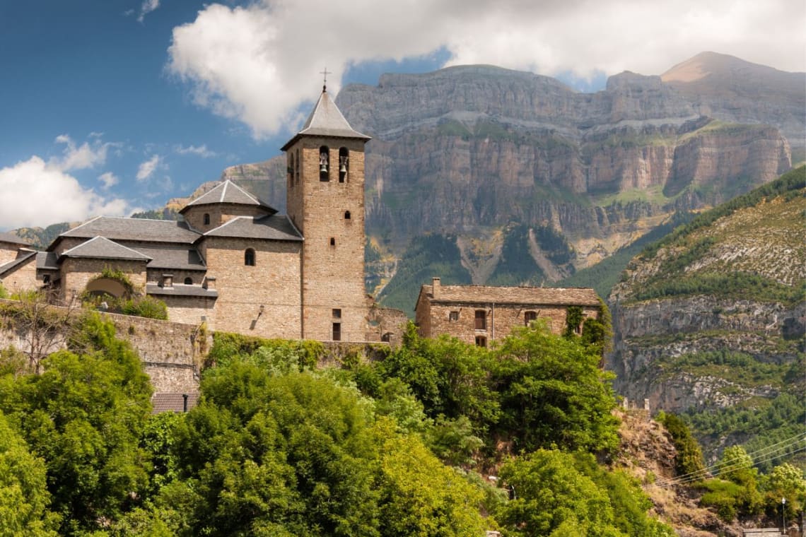 Campanario de iglesia en Torla con acantilado de omntaña detrás