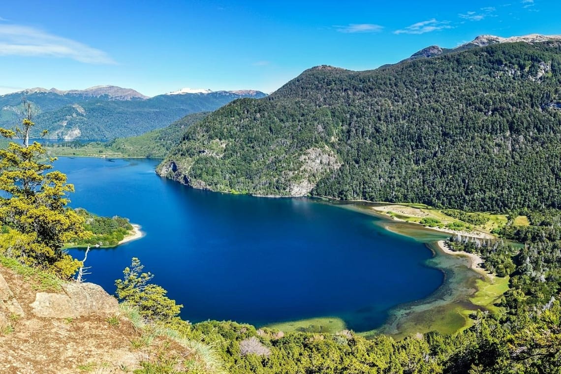 Vista desde lo alto de lago azul intenso rodeado de bosque de alerces en el Parque Nacional Los Alerces