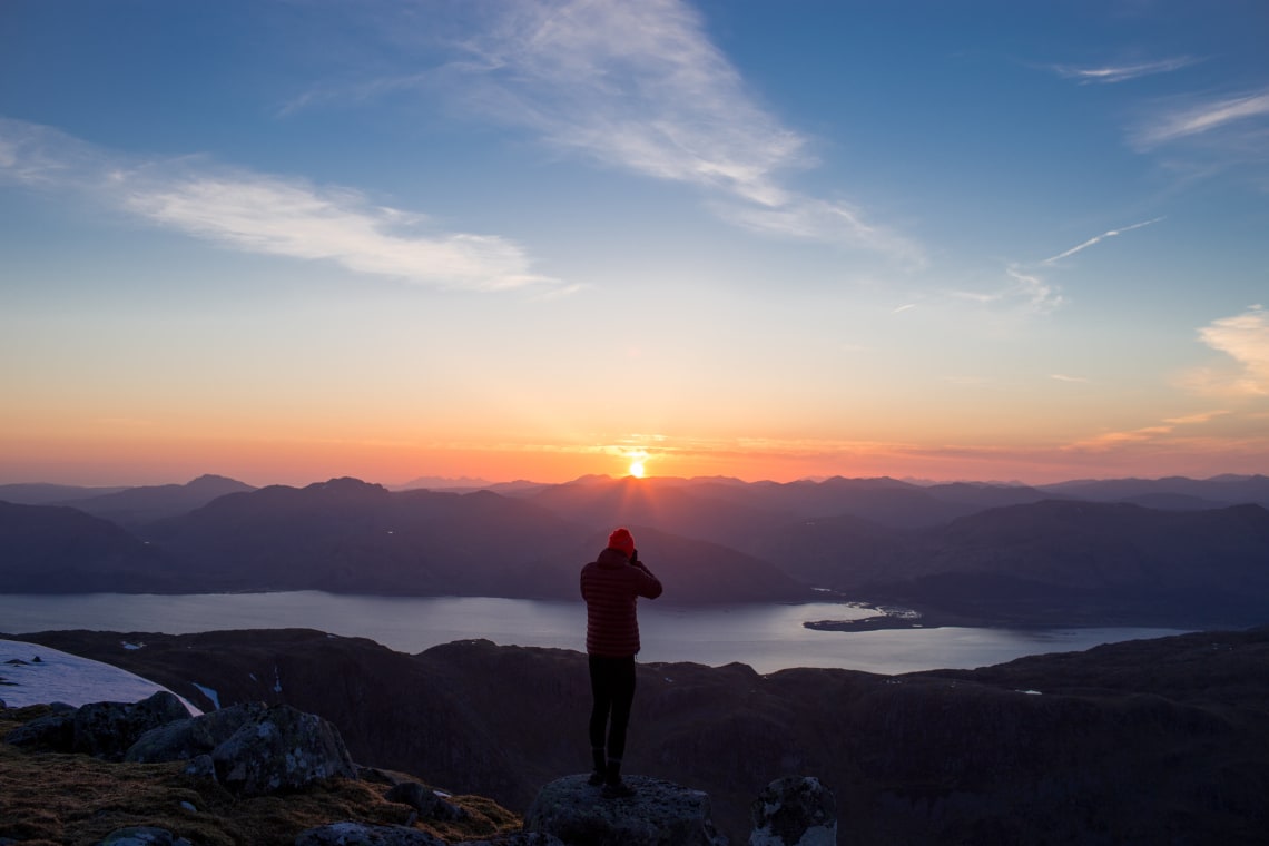 Solo traveler photographing a mountain sunrise