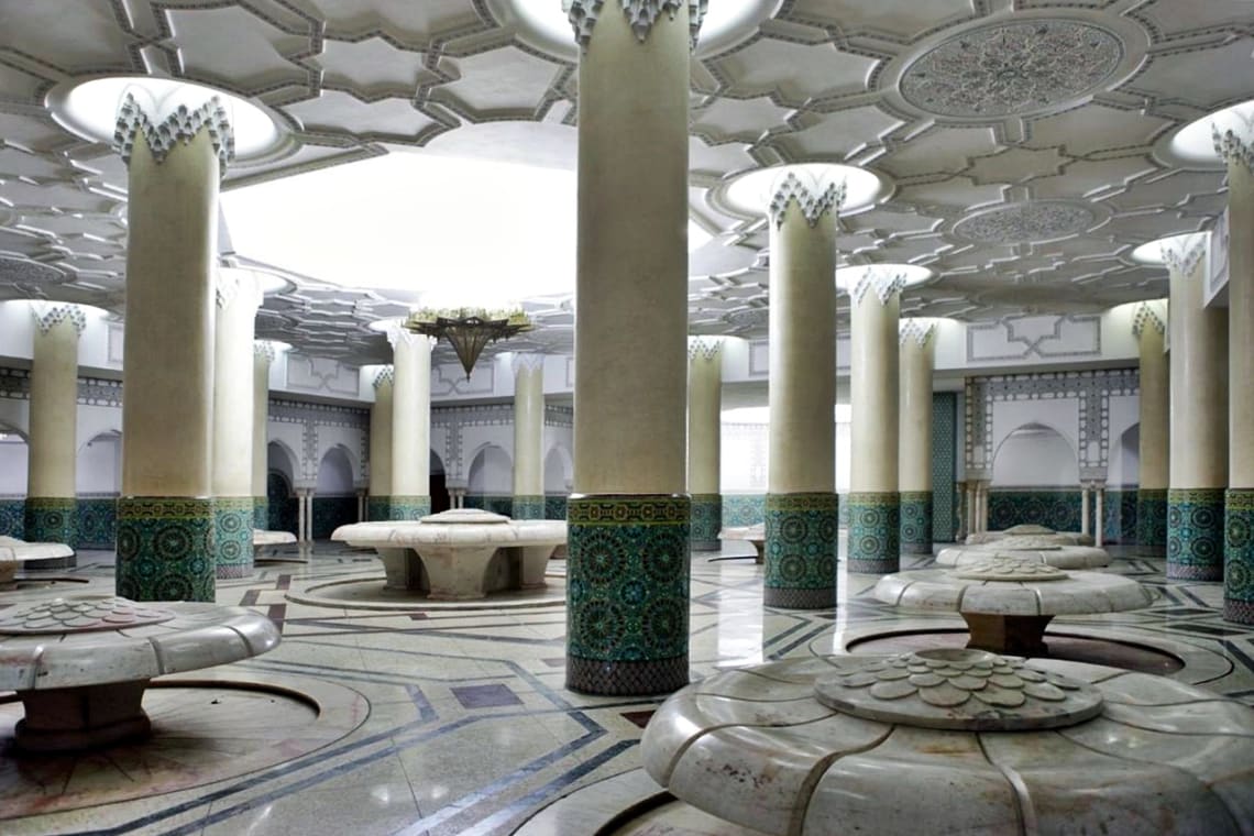 Interior de un hammam con gruesas columnas, arcos y diseños geométricos