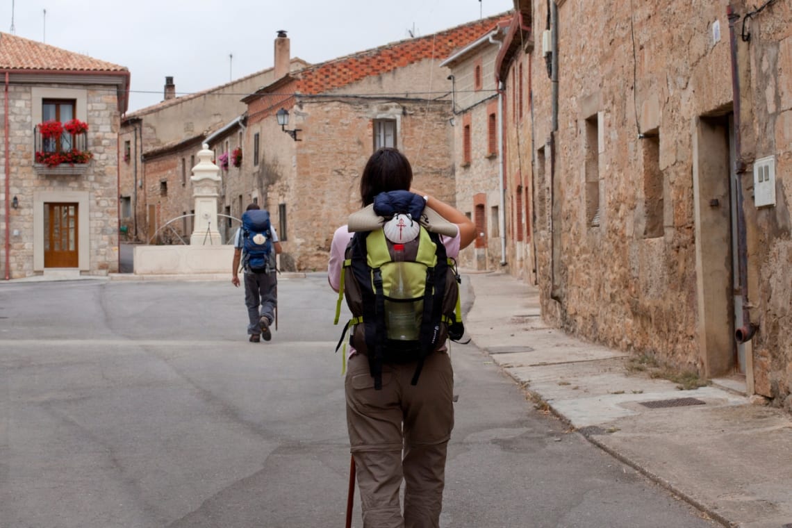 Chica caminando por un pueblo como parte del Camino de Santiago, la ruta de senderismo en España más famosa