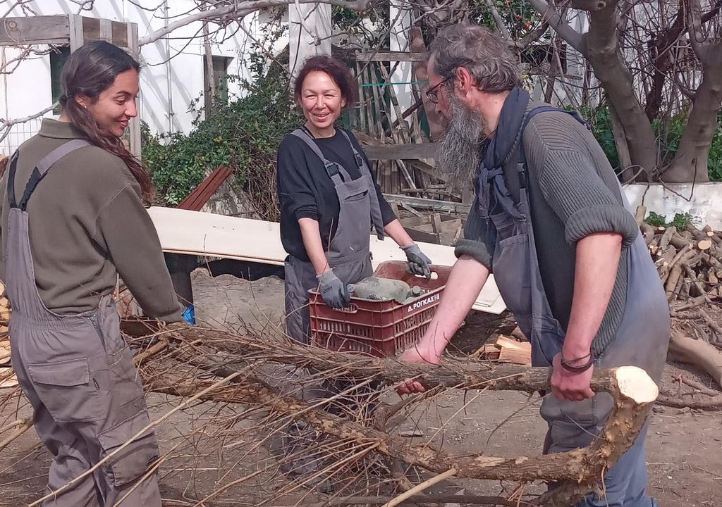 A man and two women sawing wood