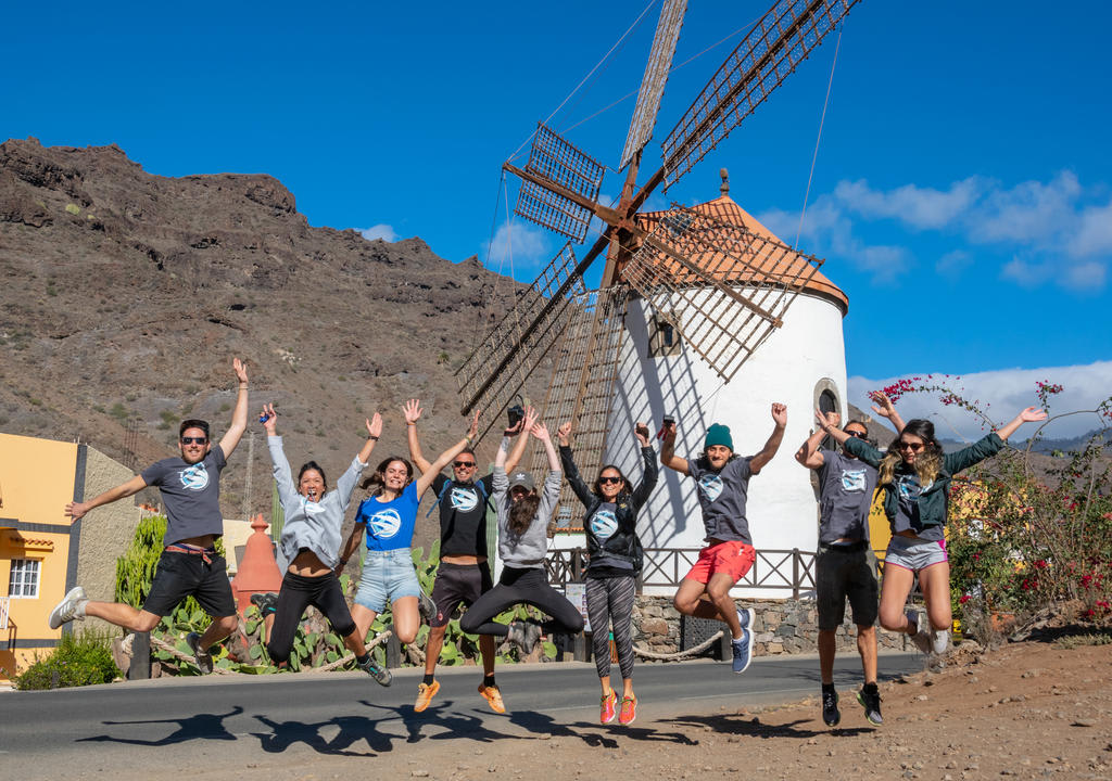 Group of volunteers jumping at the same time in front of a windmill