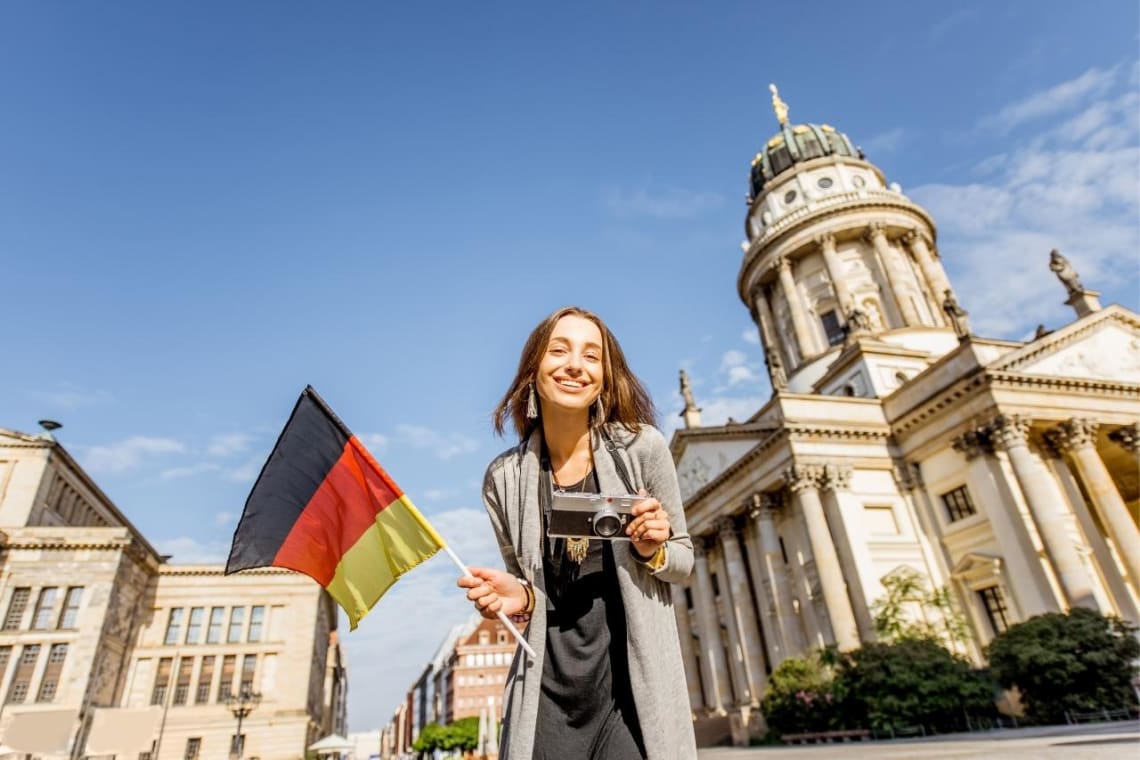 Chica con cámara en una mano y bandera de Alemania en la otra