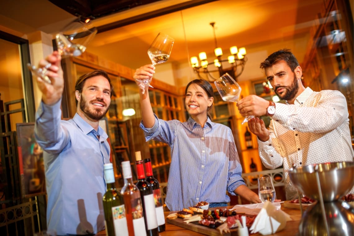 Tres jóvenes haciendo degustación de vino blanco en un viñedo en México