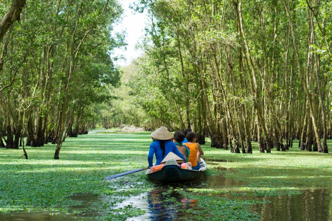 Mujer local llevando a turistas en botes como una práctica de turismo sostenible