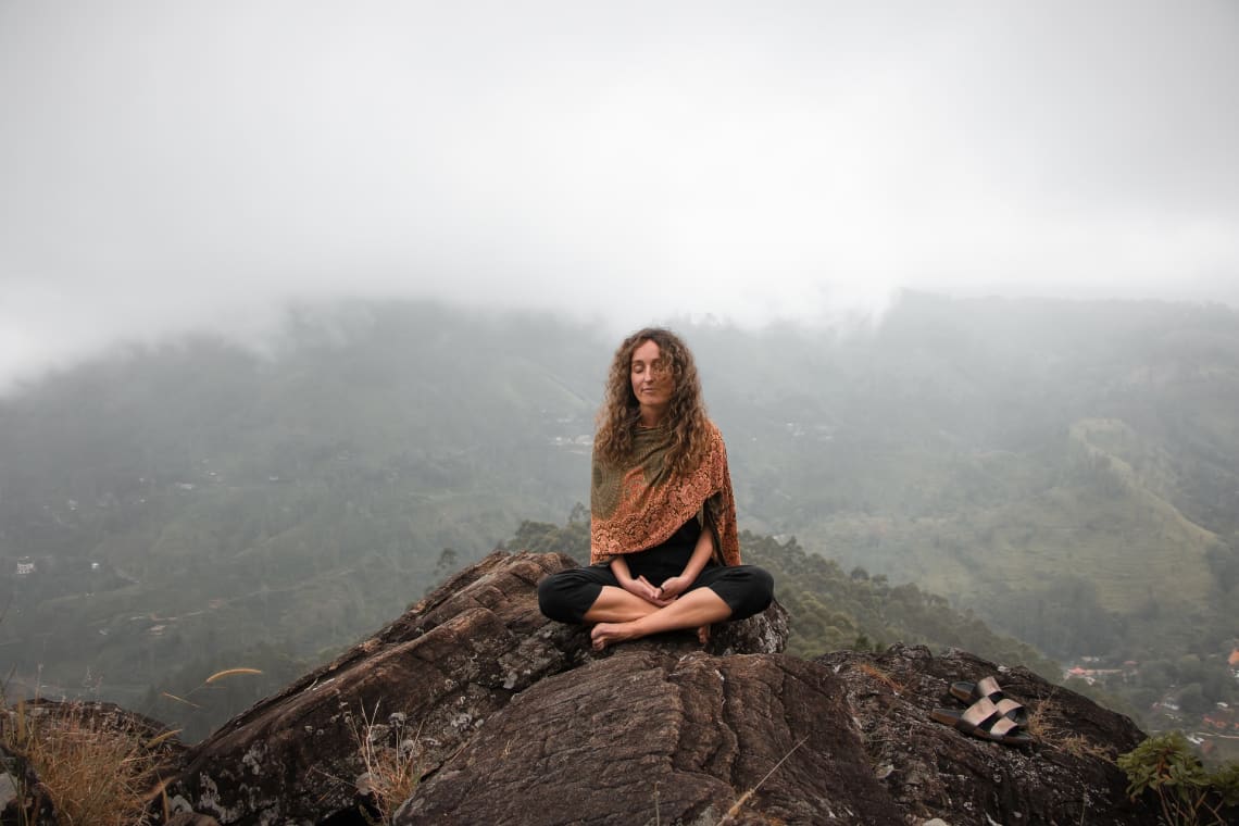 mulher meditando no topo de uma colina