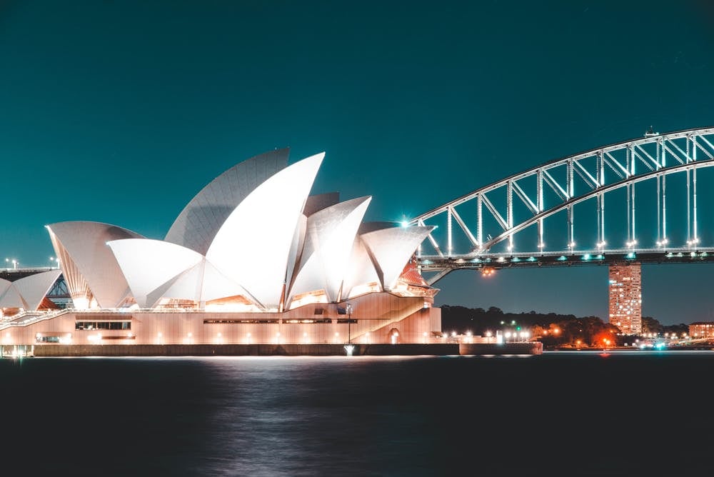 Cómo viajar barato por Australia: itinerarios, consejos y demás - Worldpackers - casa de la Opera de Sydney con puente y de noche  