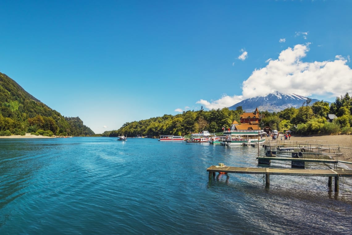 Orilla del lago Todos los Santos con muelles, embarcaciones y volcán de fondo