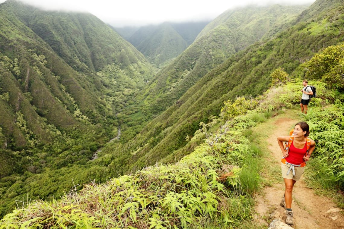 Pareja caminando por un sendero junto a un cañón natural en Hawaii