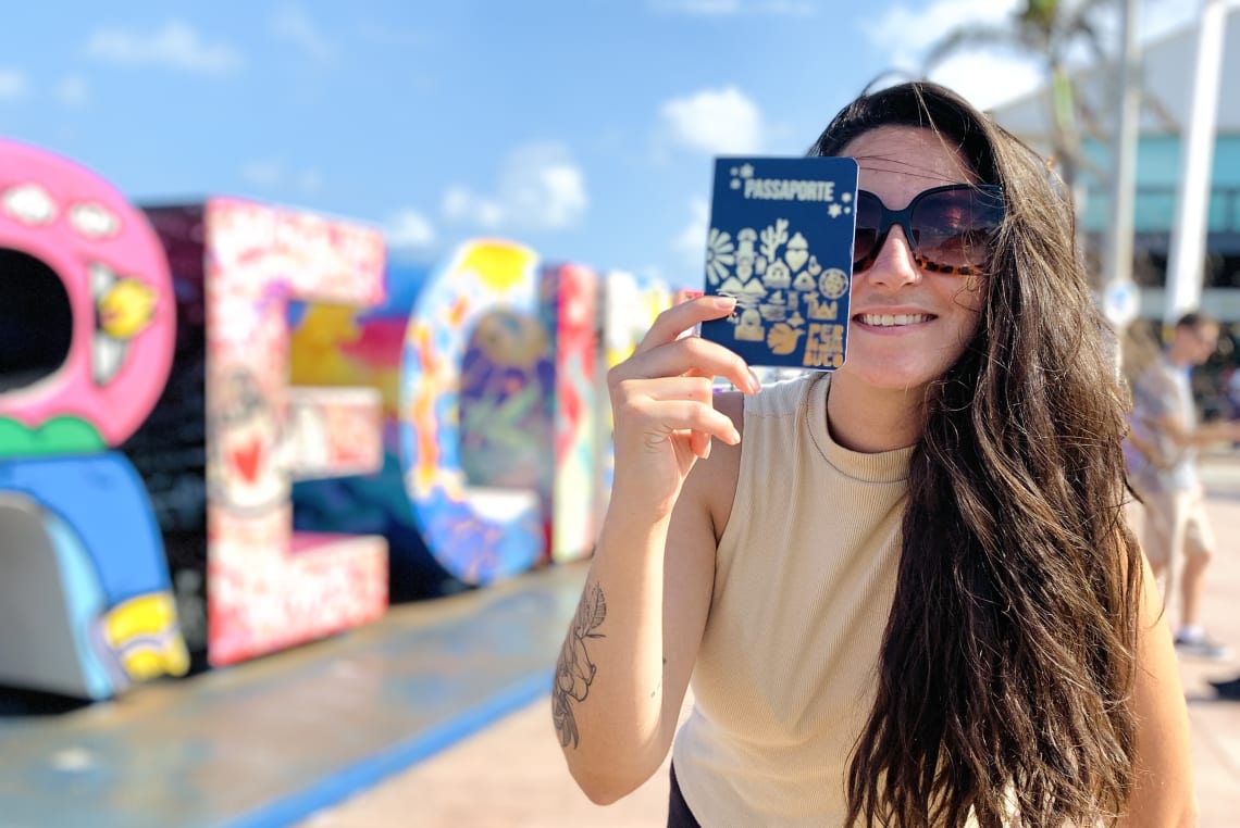 Mulher posando com passaporte Pernambuco no Marco Zero do Recife