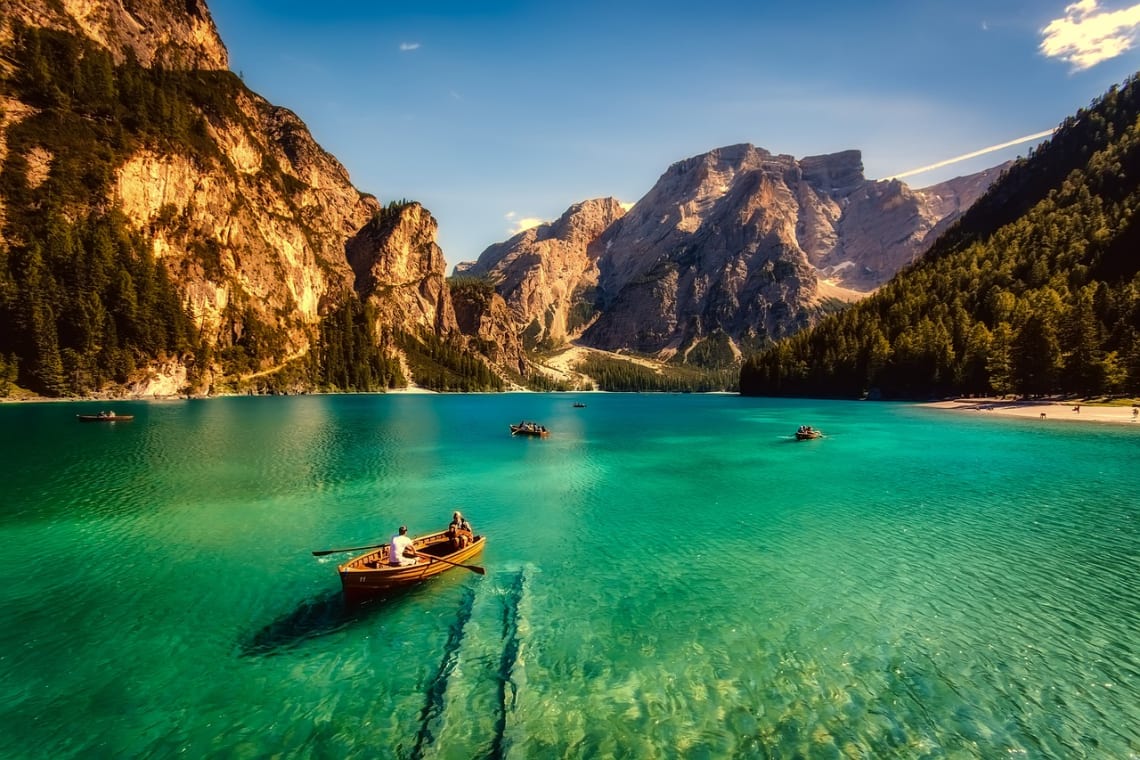 Rowboats in a turquoise lake sorrounded by mountains and pine trees