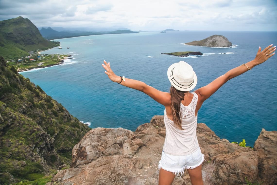 Chica en un mirador con vista al mar desde lo alto en Hawaii