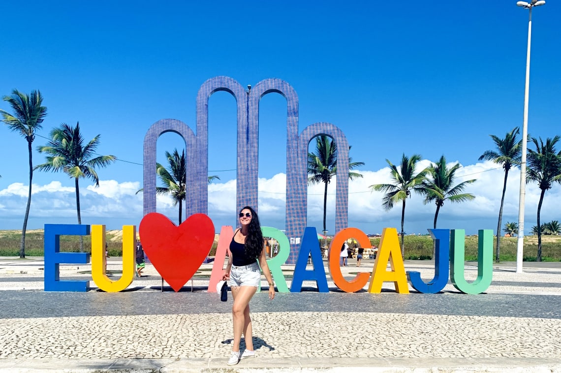 Mulher posando em frente ao letreiro de Aracaju, SE