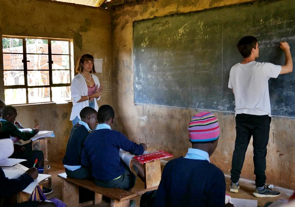 Dos jóvenes voluntarios dando clases en una escuela rural en África
