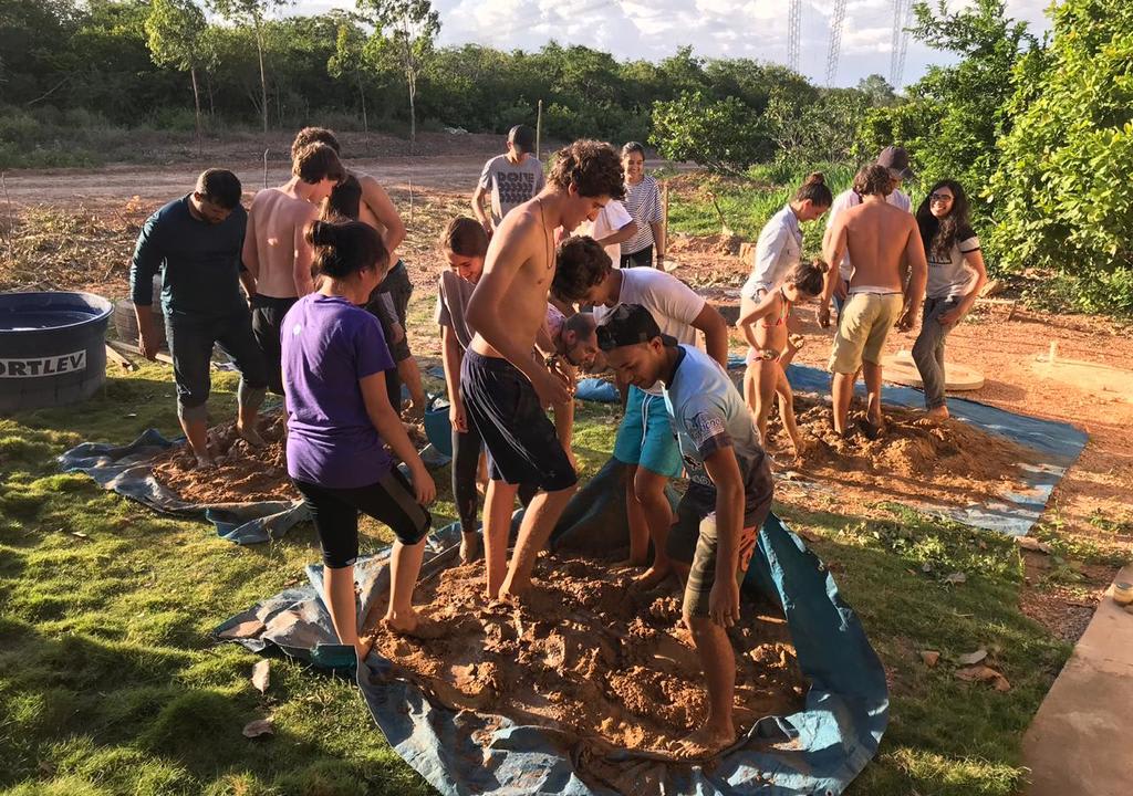 Grupo de jóvenes pisando tierra para preparar material de ecoconstrucción 