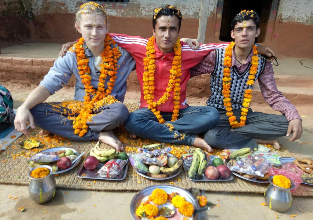 Cultural exchange: Young western guy hugging two Nepalese during a religious celebration