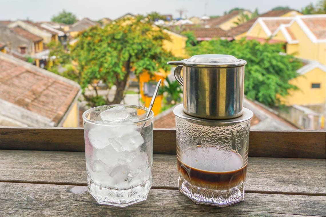 Vaso con café vietnamita y filtro metálico sobre este, y otro vaso con hielo al lado