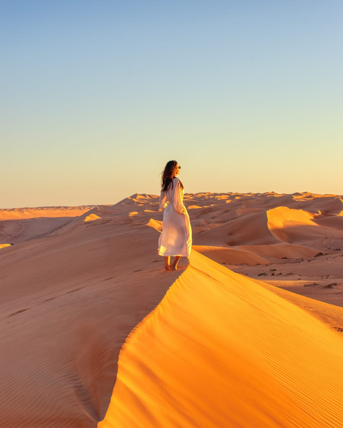 Solo female traveler watching a desert sunset