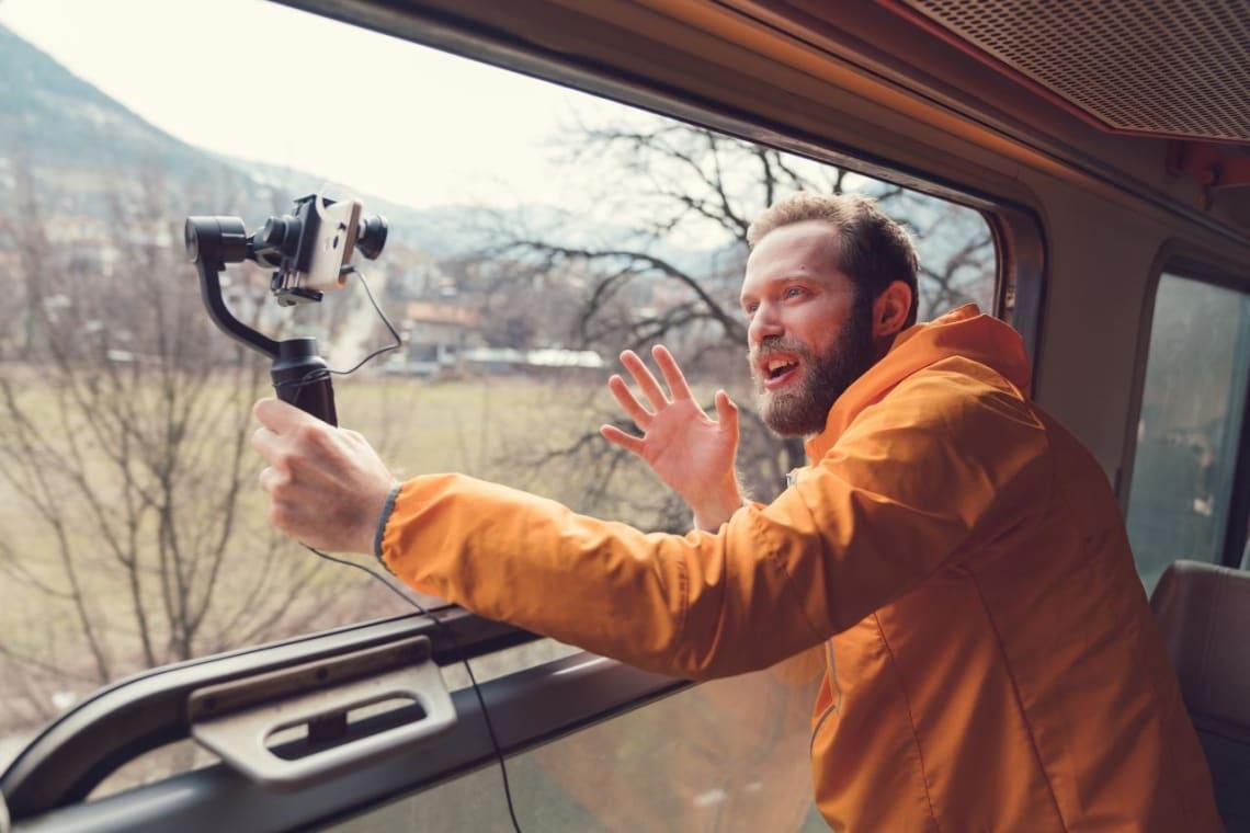 Guy next to a train window filming himself with a phone