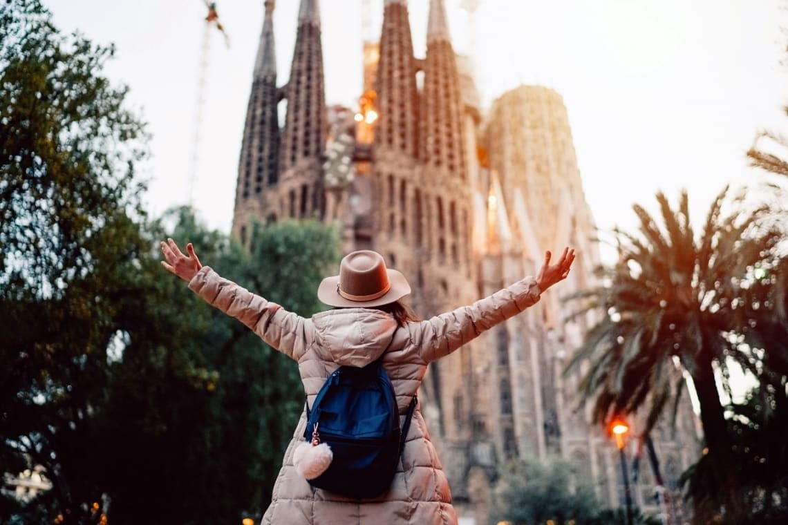 Viajera con los brazos abiertos frente a la Sagrada Familia de Barcelona