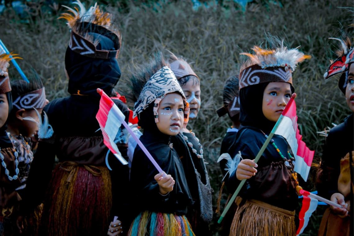 Niños indonesios con vestimenta tradicional y banderas