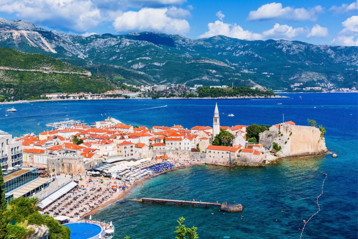 Red roofed houses and the beach sorrounded by mountains in Budva