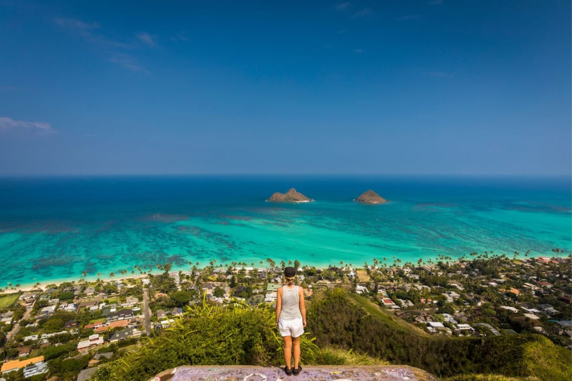 Chica desde un mirador observando la playa Lanikai desde lo alto