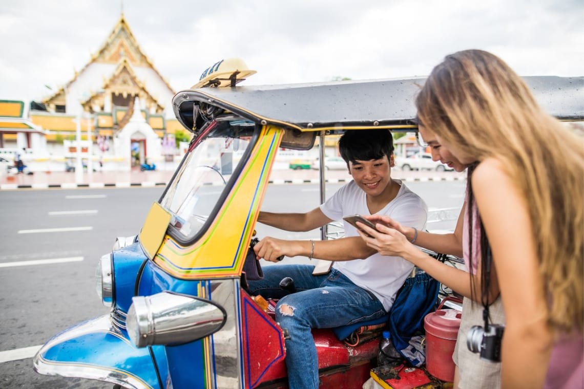 Dos turistas negociando con conductor de tuk-tuk