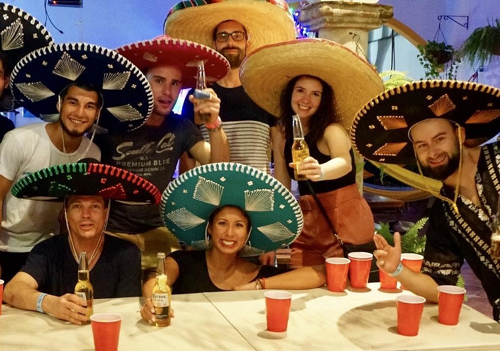 Jóvenes extranjeros con sombreros mexicanos y cerveza festejando