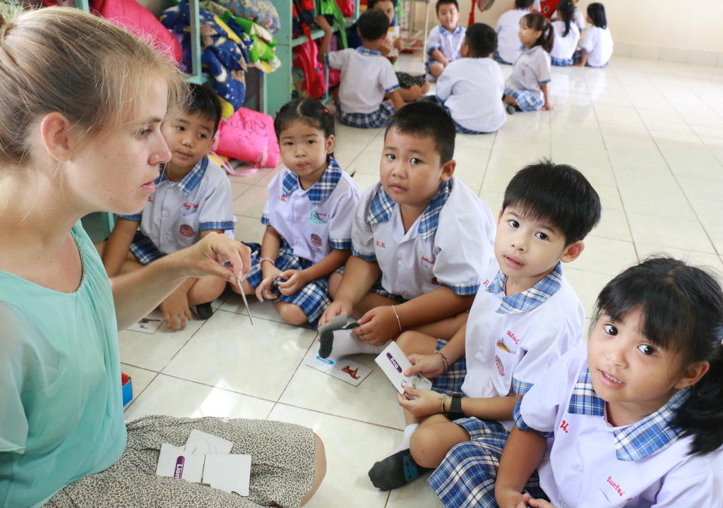 Young western girl teaching English to thai kids