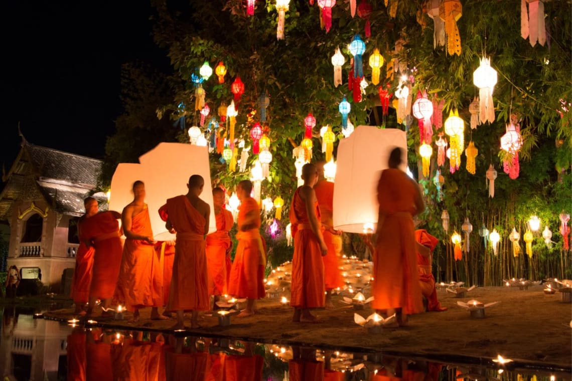 Monjes budistas con lámparas durante festival en Chiang Mai