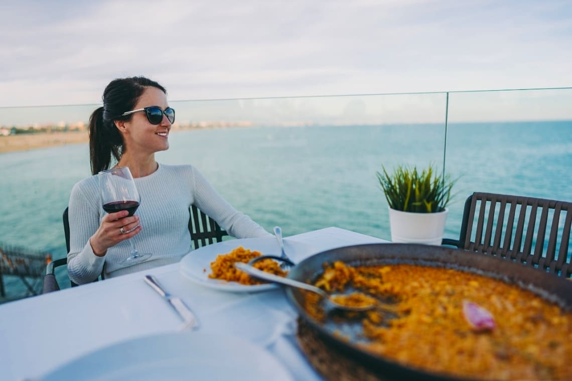 Girl having a paella and a glass of wine in Spain as part of her vacation alone