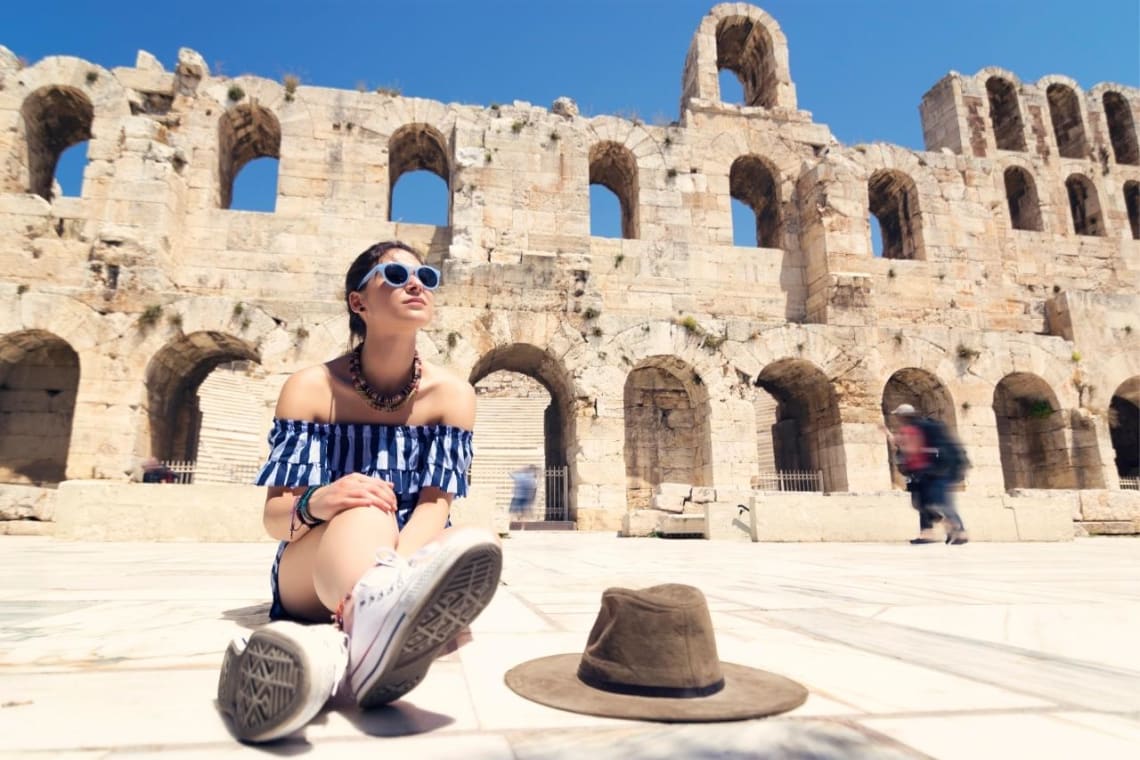 Girl seated in front of archeological complex in Athens, Greece