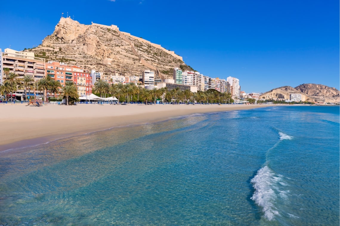 Playa de Alicante con monte donde se encuentra el castillo de fondo