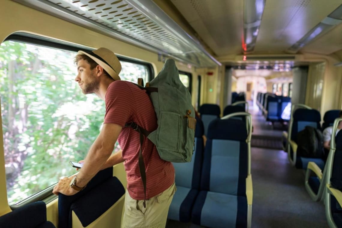 Joven viajando ligero en tren con mochila