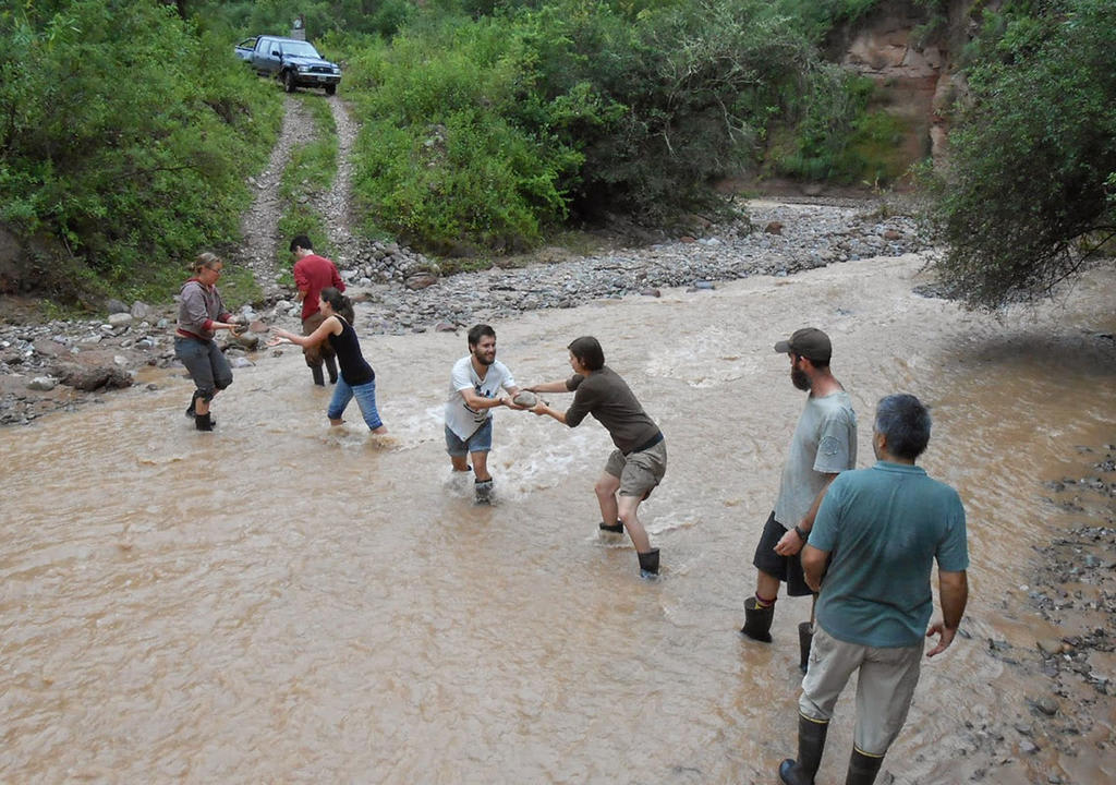 Group of volunteers from a environmental project removing stones from a river to let a van cross