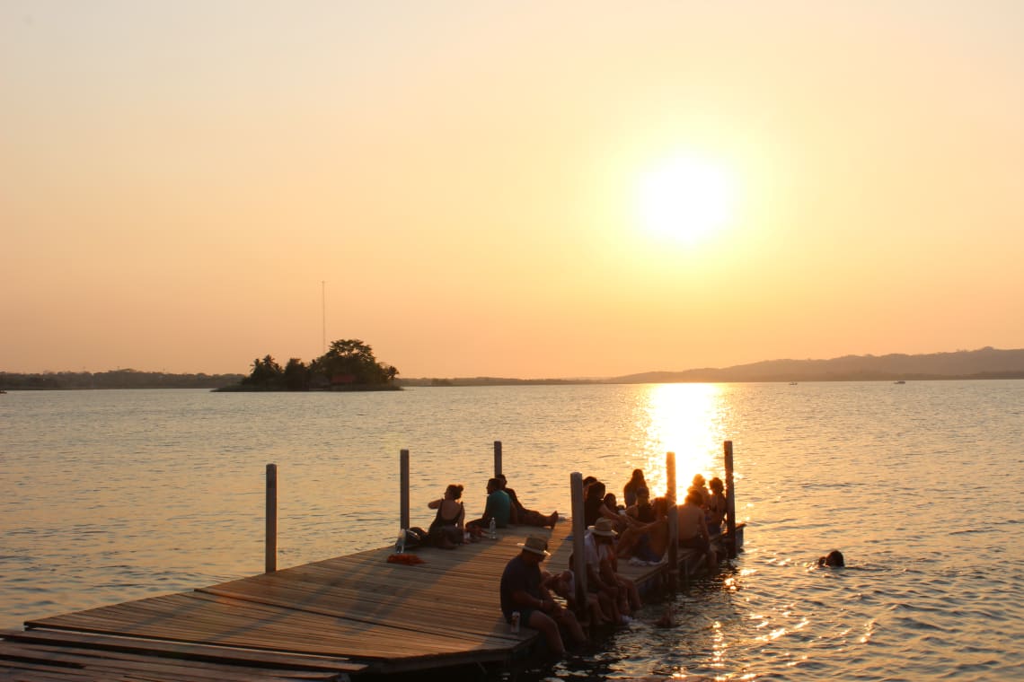 Gente sentada en el muelle disfrutando de un atardecer