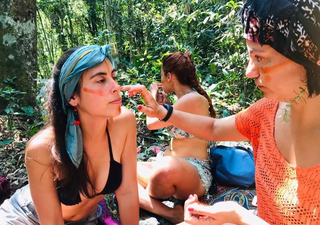 Mujer pintándole la cara a otra con productos naturales en la selva