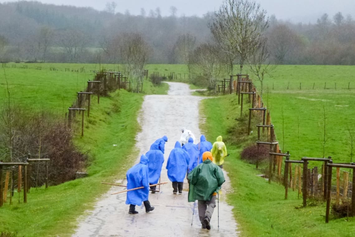 Peregrinos con impermeable haciendo el Camino de Santiago bajo la lluvia