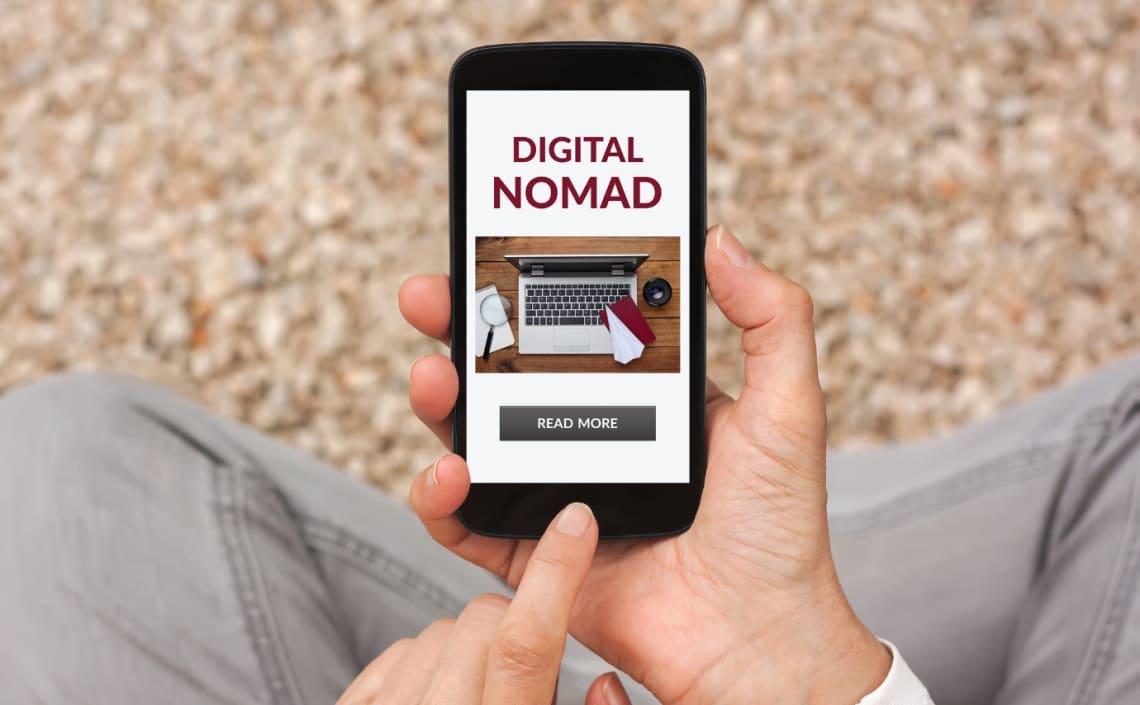 Manos de hombre sosteniendo celular con pantalla que dice "Digital Nomad"